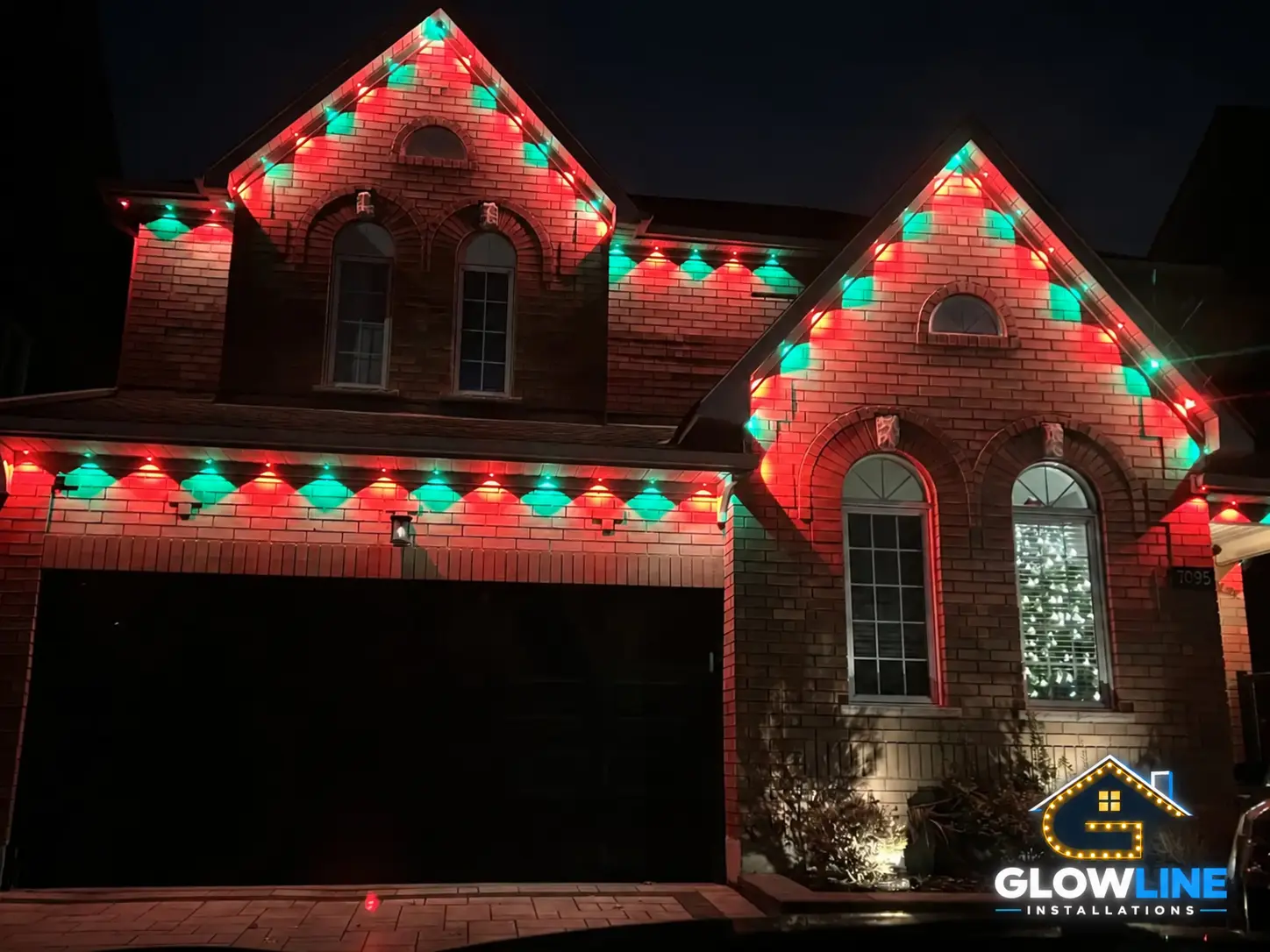 Brick home with red and green Christmas permanent lights