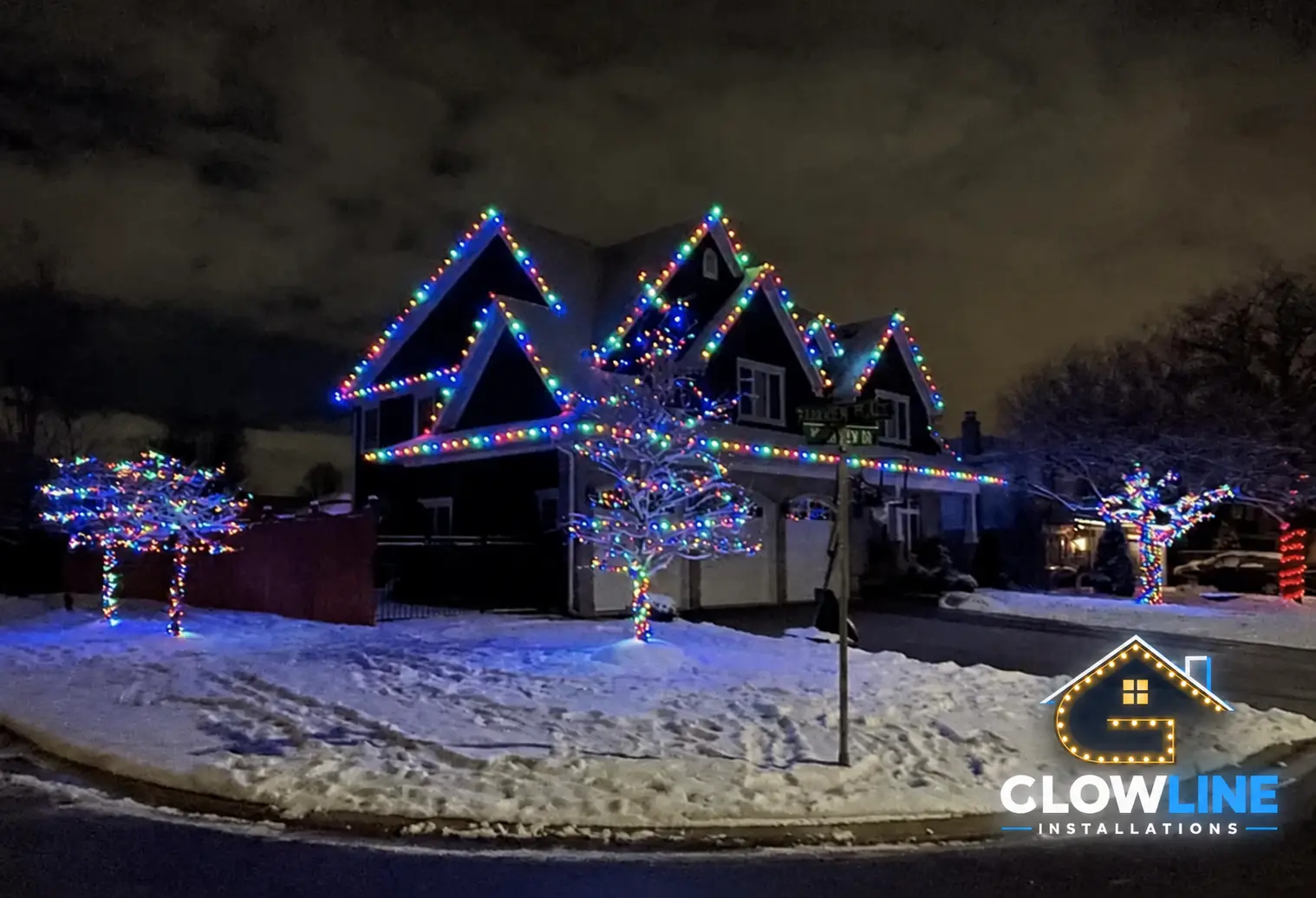 Permanent Christmas outdoor lights installed on a snow-covered home